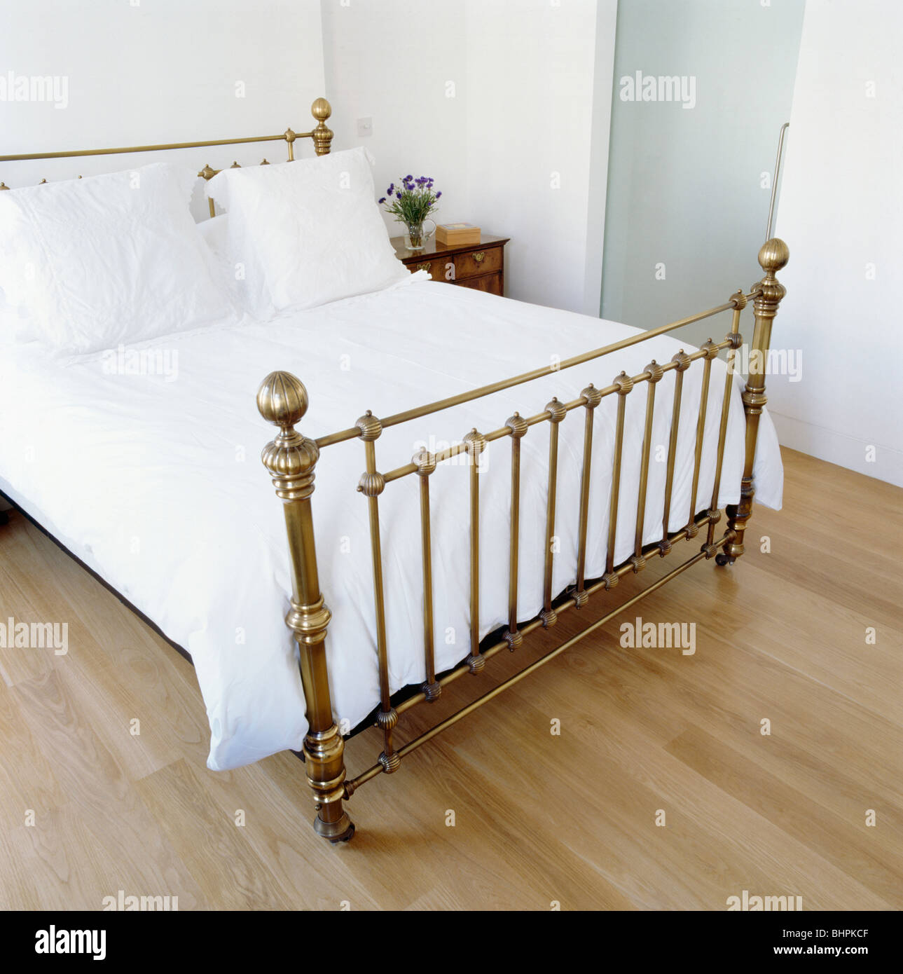 Laiton antique lit avec couette et oreillers blanc en blanc chambre avec parquet au sol Banque D'Images