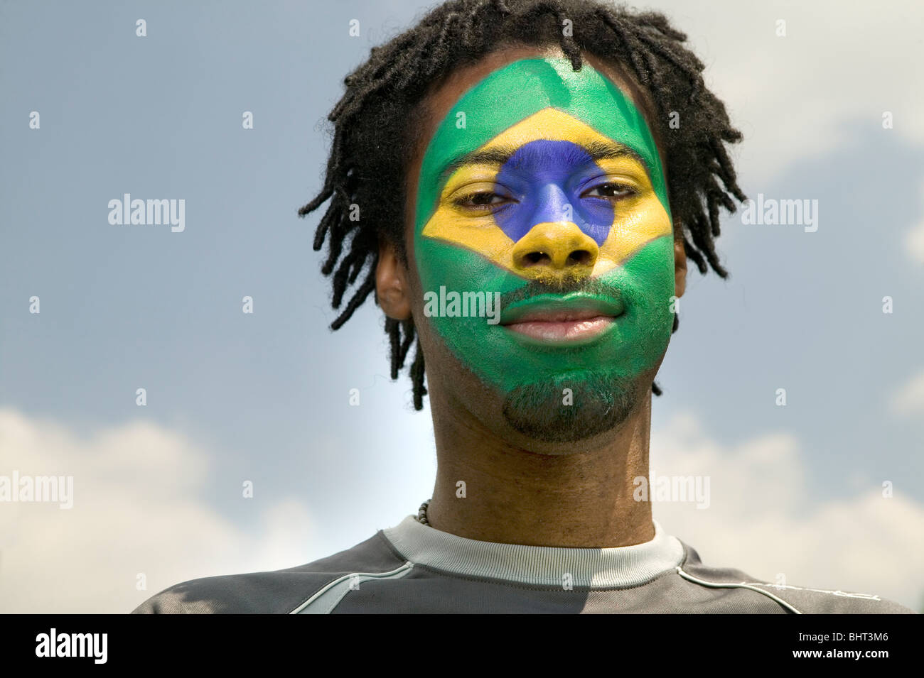 Un supporter de football Brésil patriotique avec le drapeau du Brésil peint sur son visage Banque D'Images