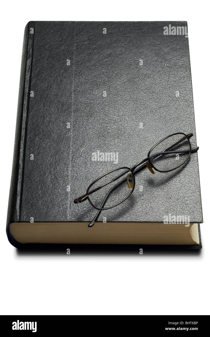Un livre relié avec des lunettes de lecture sur - chemin de détourage Banque D'Images