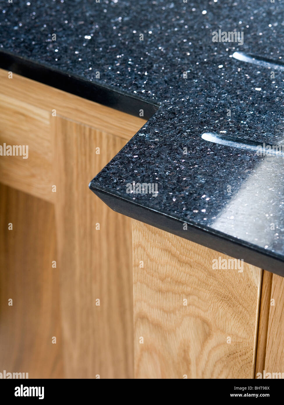 Close-up de granit noir du plan de travail sur l'unité de cuisine en bois pâle Banque D'Images
