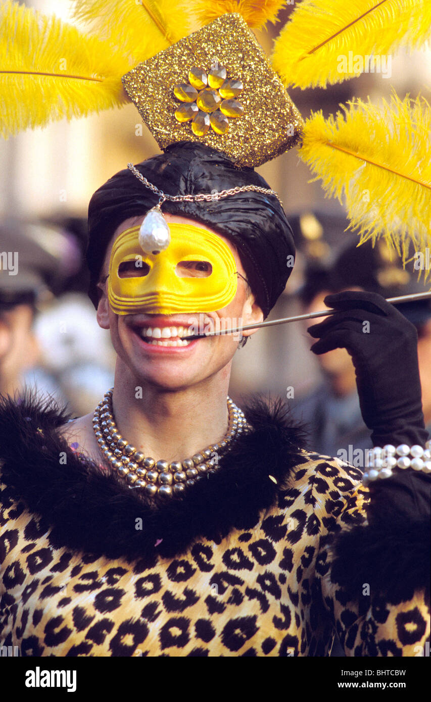 Croix de l'homme habillé en robe à motifs peau de léopard, masque jaune et porte-cigarette longue tenue à la Carnaval de Venise Banque D'Images