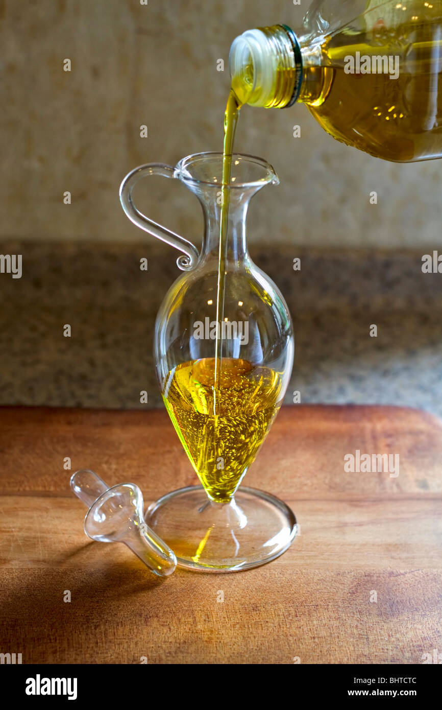 L'huile d'olive est versé dans un pot de sauce à salade Banque D'Images