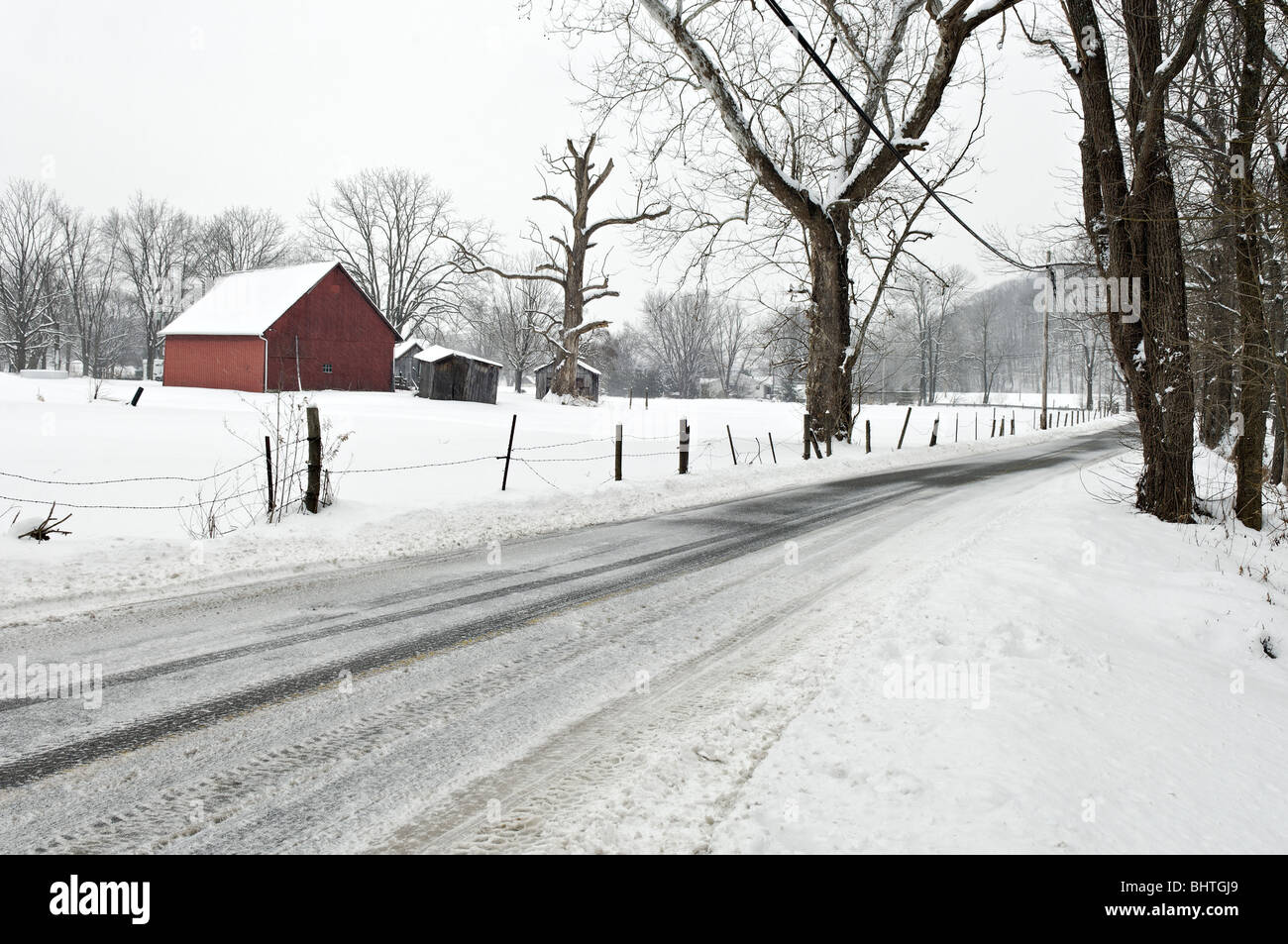 Grange rouge, d'une clôture et de la route de comté dans la neige dans Floyd Comté (Indiana) Banque D'Images