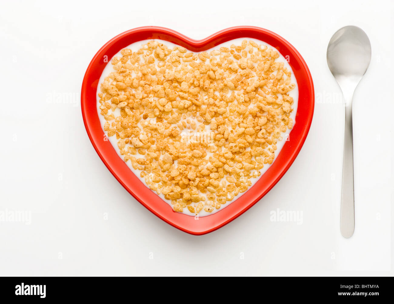 Plat Lay studio photo d'un bol de Rice Krispies en forme de cœur rouge et de lait sur fond blanc, tiré d'en haut. Banque D'Images