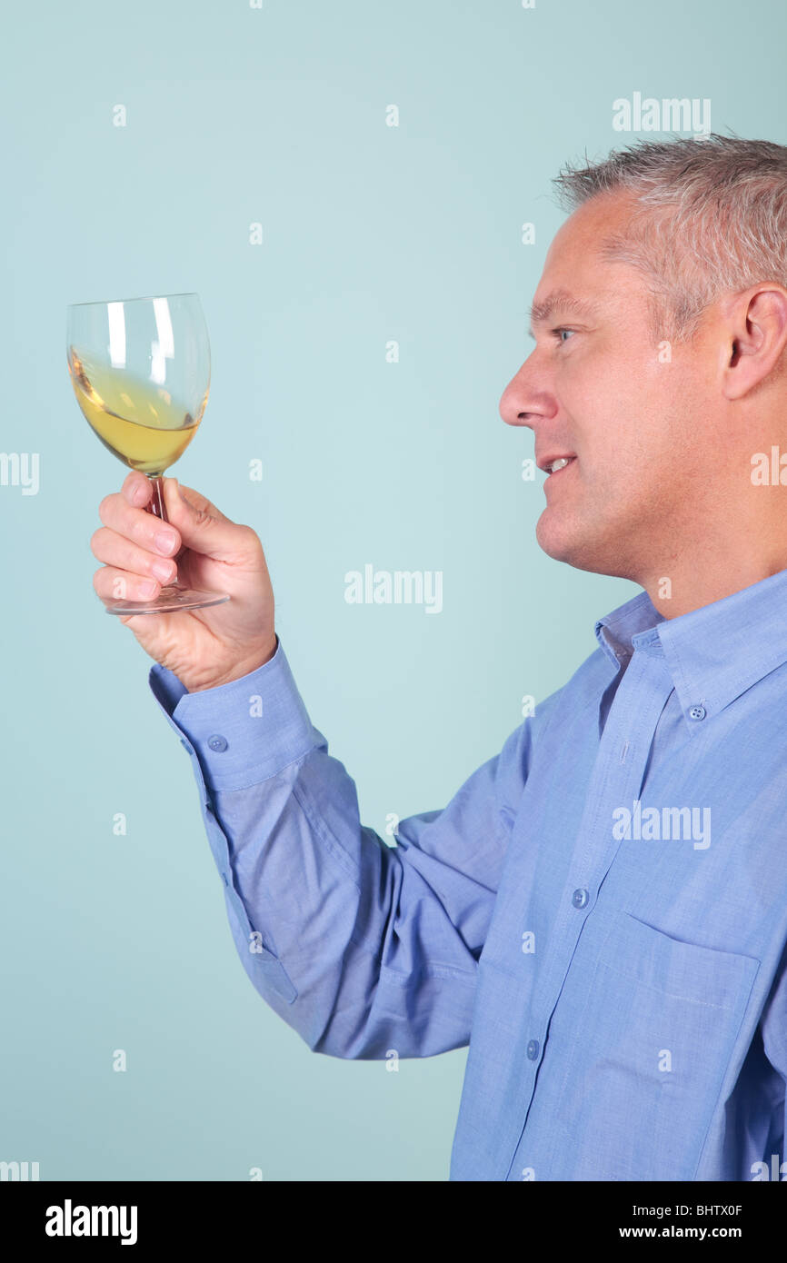 Homme tenant un verre de vin blanc pour plus de clarté et de contrôle qualité. Banque D'Images
