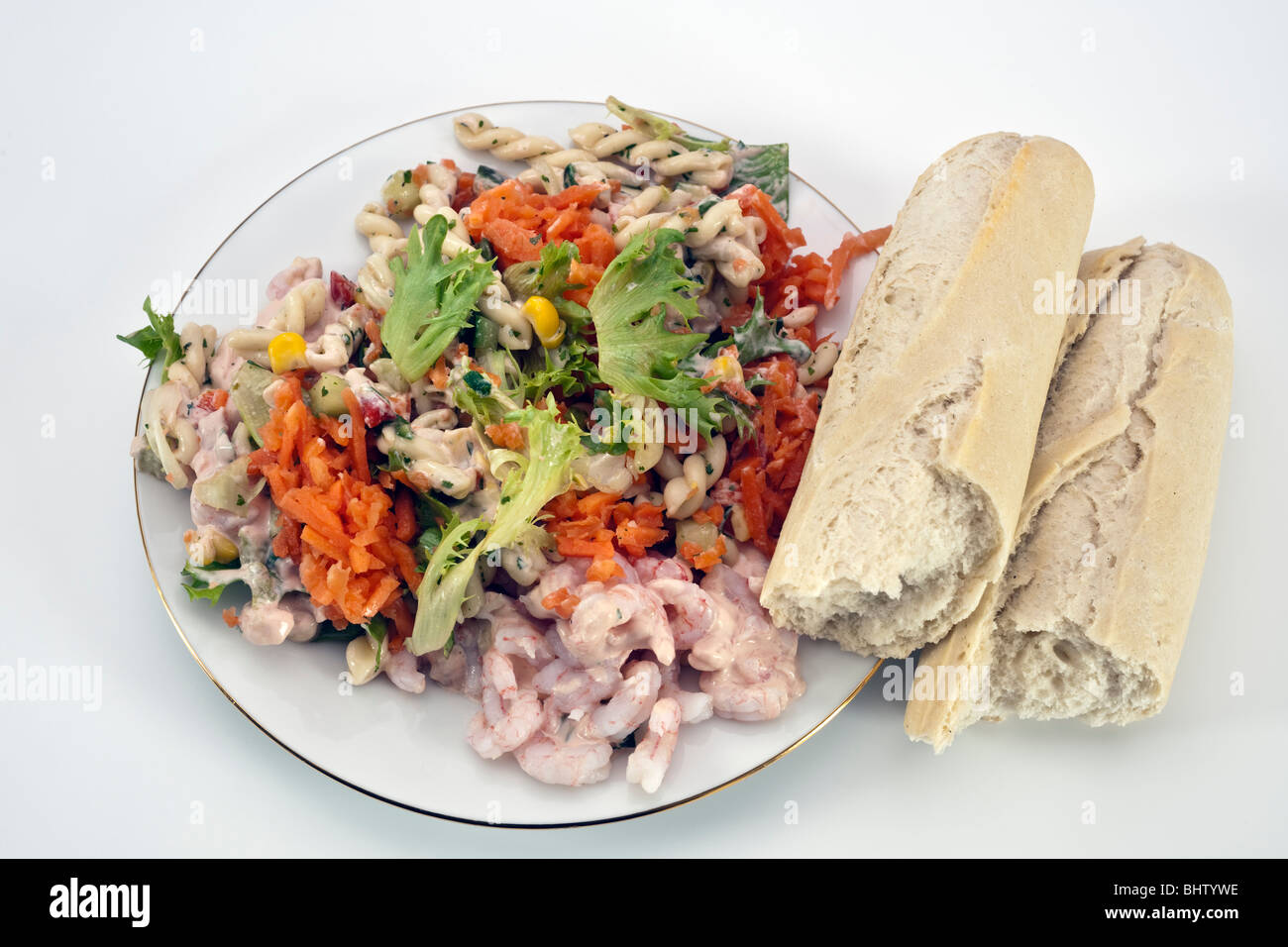 Salade de langoustines et de pâtes sur une plaque blanche avec une baguette brisée Banque D'Images