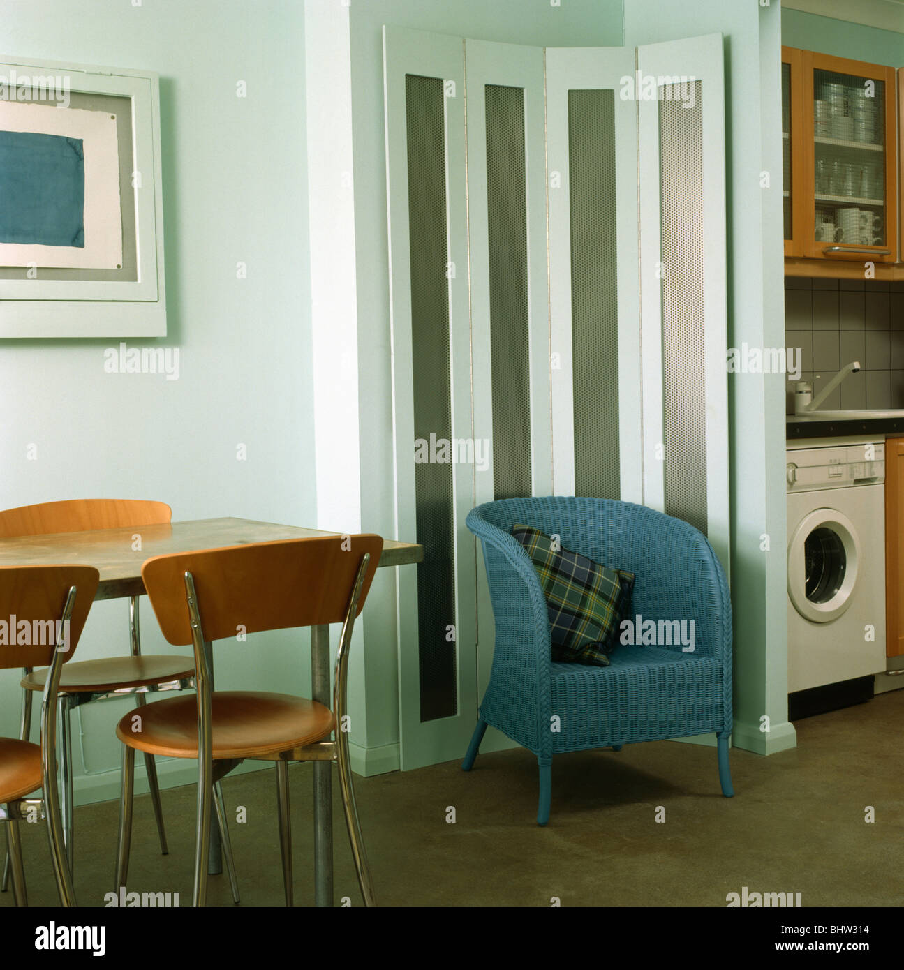 Fauteuil bleu en face de paravent au coin de studio moderne avec table à manger et chaises Banque D'Images