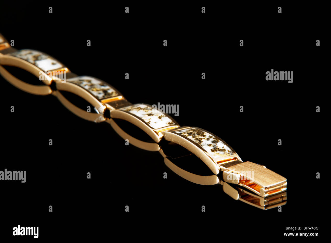 Ce libre est un bracelet en or avec des paillettes d'or intégré sur un fond noir avec reflet de la joaillerie. Banque D'Images
