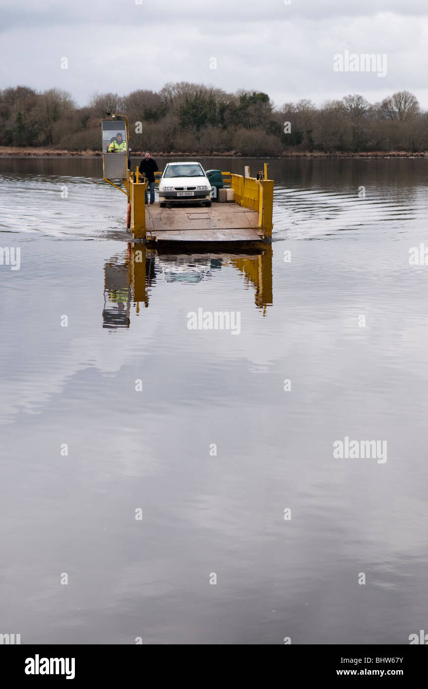 Petit ferry sur un lac avec une voiture et des passagers à bord. Banque D'Images