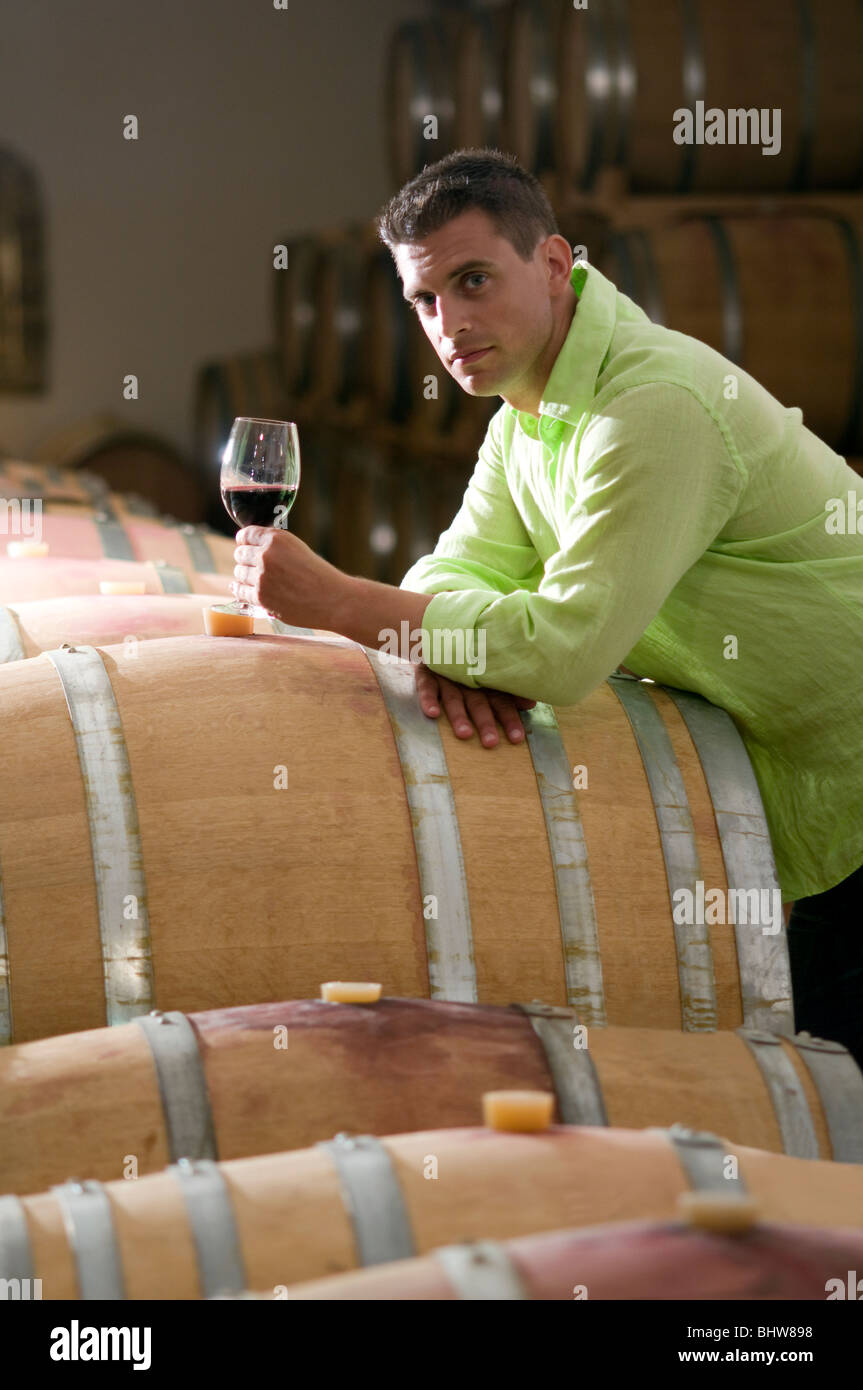 Jeune homme dans la cave à vin avec verre de vin rouge Banque D'Images