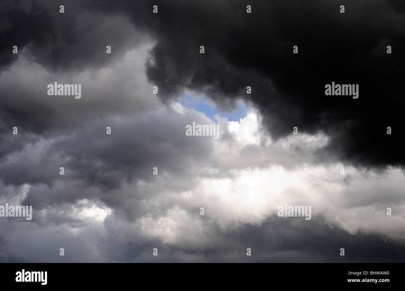 Un patch de ciel bleu à travers les nuages thunder noir et gris. Bedgebury Forêt, Kent, UK. Banque D'Images