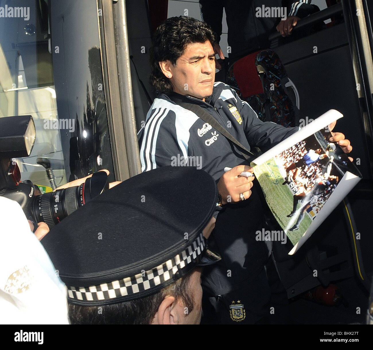 La légende du football argentin et nouvel entraîneur-chef de l'équipe nationale, Diego Maradona la signature d'une photo de sa fameuse main de Dieu but contre l'Angleterre dans la Coupe du Monde 1986 comme il arrive à l'aéroport de Glasgow en avance sur l'Ecosse v Argentine international amical à Hampden Park. 16 novembre 2008. Banque D'Images