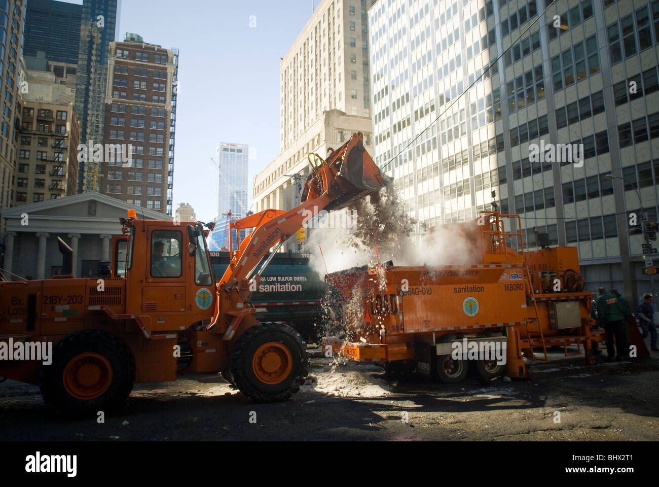 NYC Department de l'assainissement des travailleurs utilisent un chargeur avant de déposer des montagnes de neige dans un fondeuse à neige dans le Lower Manhattan à New York Banque D'Images