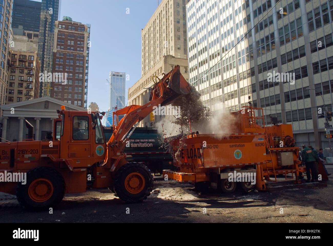 NYC Department de l'assainissement des travailleurs utilisent un chargeur avant de déposer des montagnes de neige dans un fondeuse à neige dans le Lower Manhattan à New York Banque D'Images