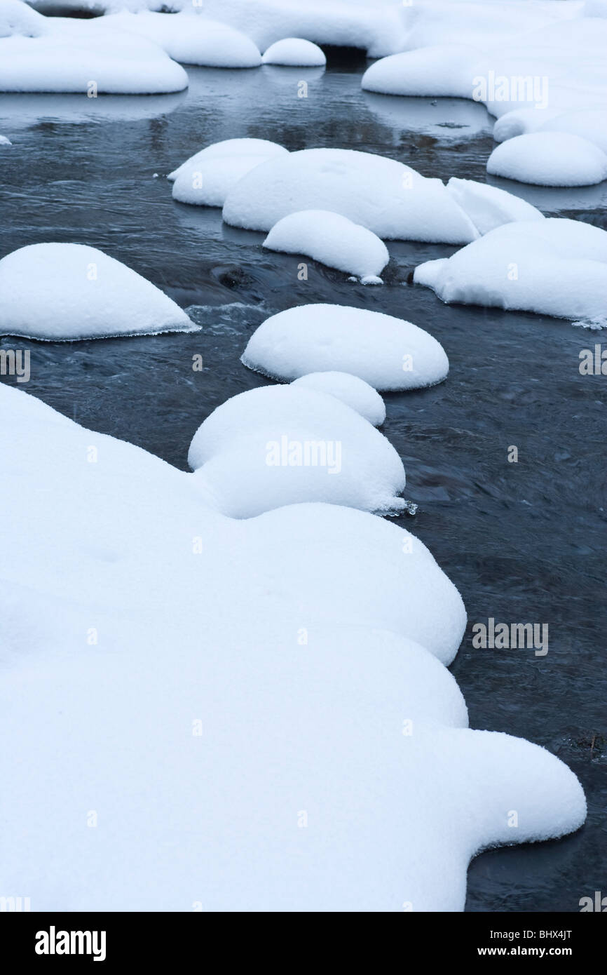 La neige a couvert des pierres dans la rivière Banque D'Images