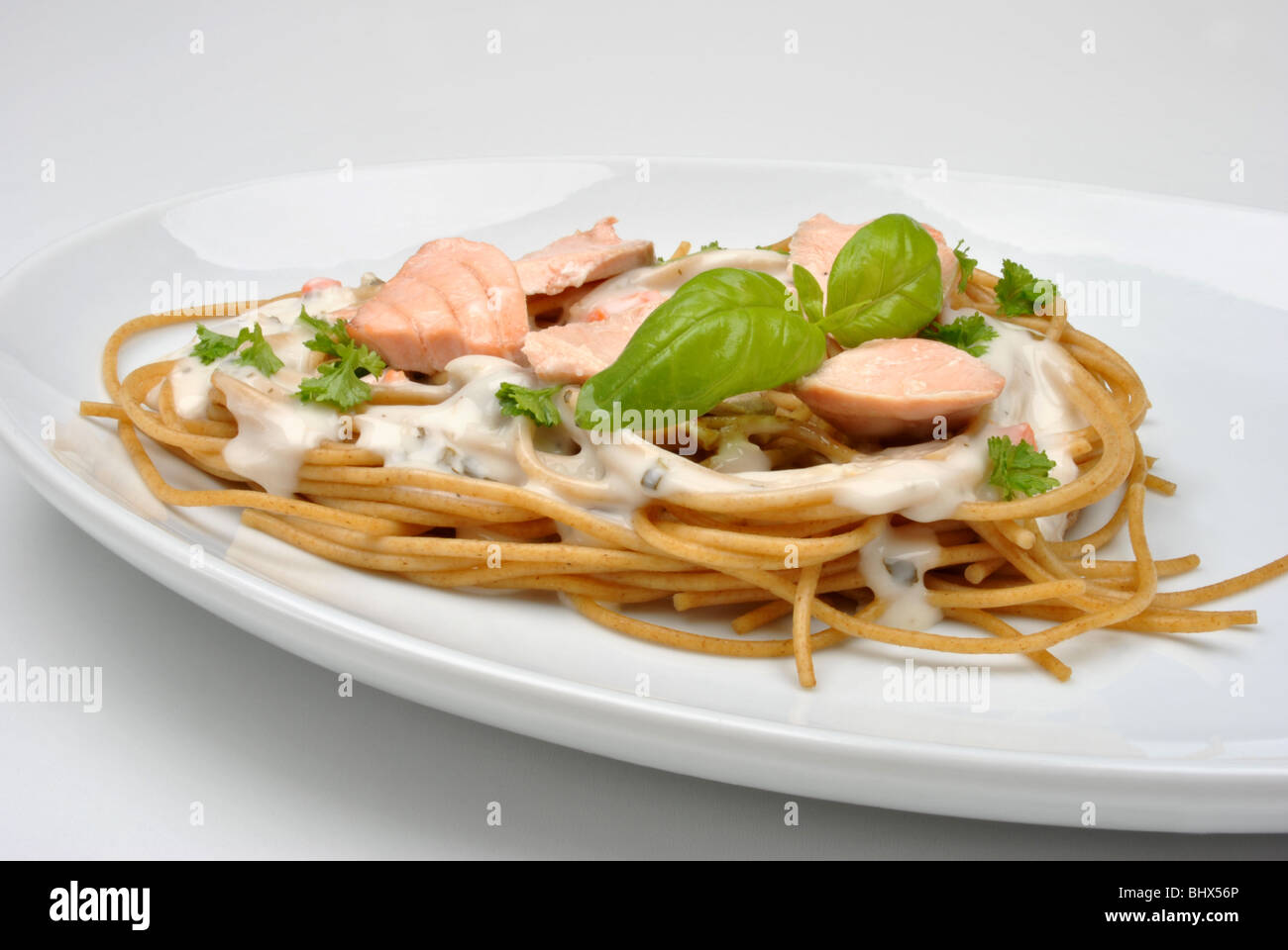 Le spaghetti cuit avec du saumon bio et basilic Banque D'Images