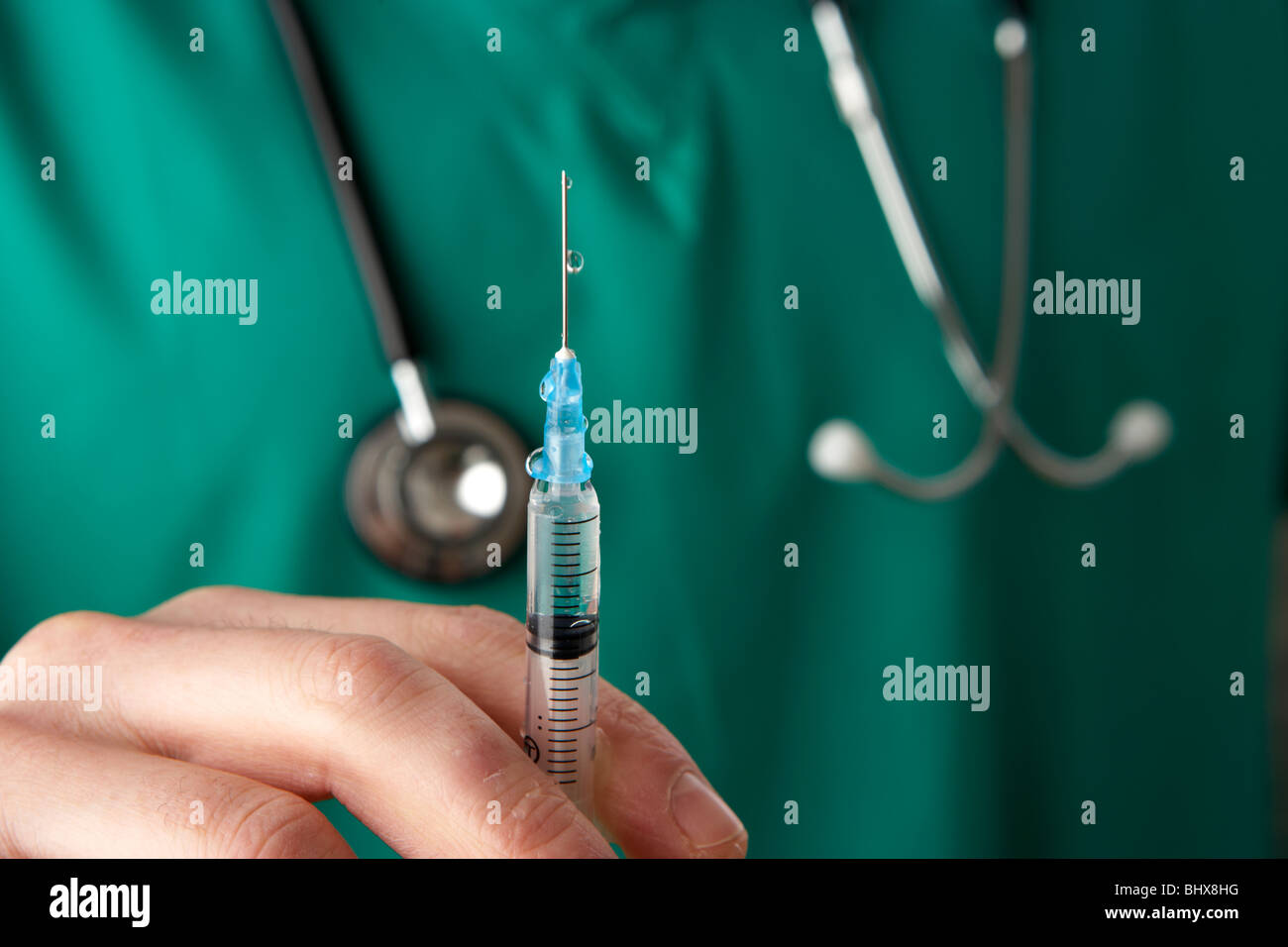 Man wearing scrubs medical stéthoscope et tenir l'aiguille et la seringue contenant du liquide Banque D'Images