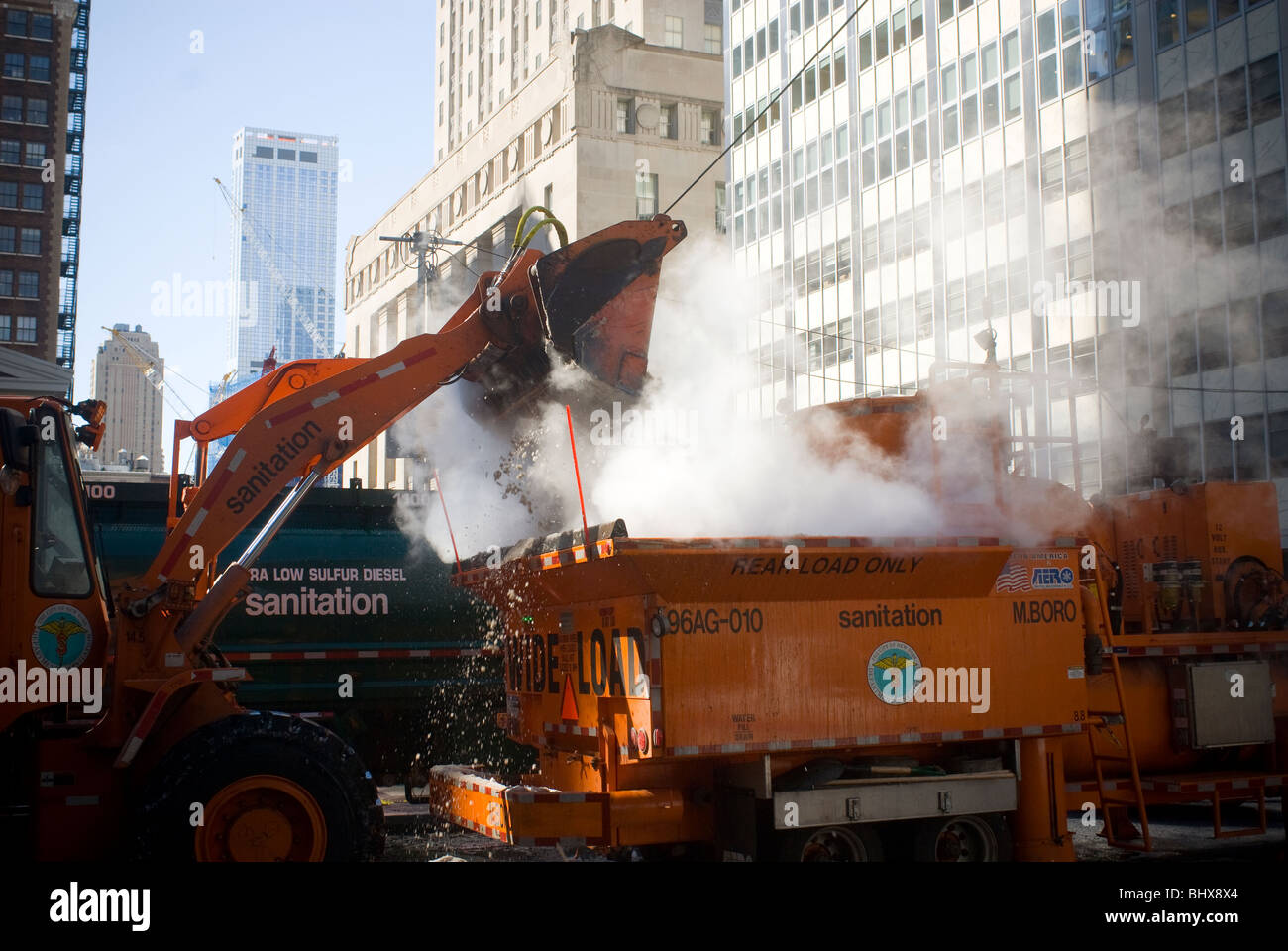 NYC Department de l'assainissement des travailleurs utilisent un chargeur avant de déposer des montagnes de neige dans un fondeuse à neige dans le Lower Manhattan à New York Banque D'Images