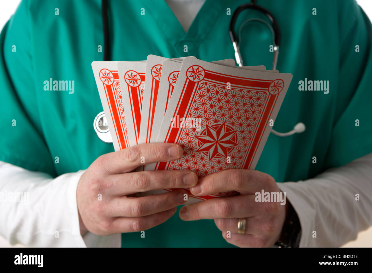 Man wearing scrubs medical stéthoscope et la tenue d'une série de cartes à jouer Banque D'Images