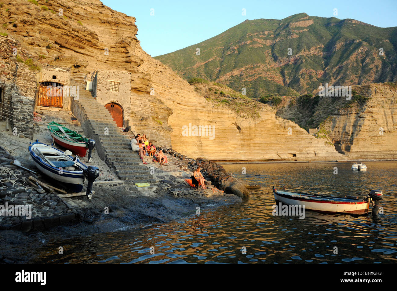 Une famille italienne assis sur les marches de pierre menant à la lagune en dessous du village de Pollara, sur l'île de Salina, Iles Eoliennes, Sicile, Italie. Banque D'Images