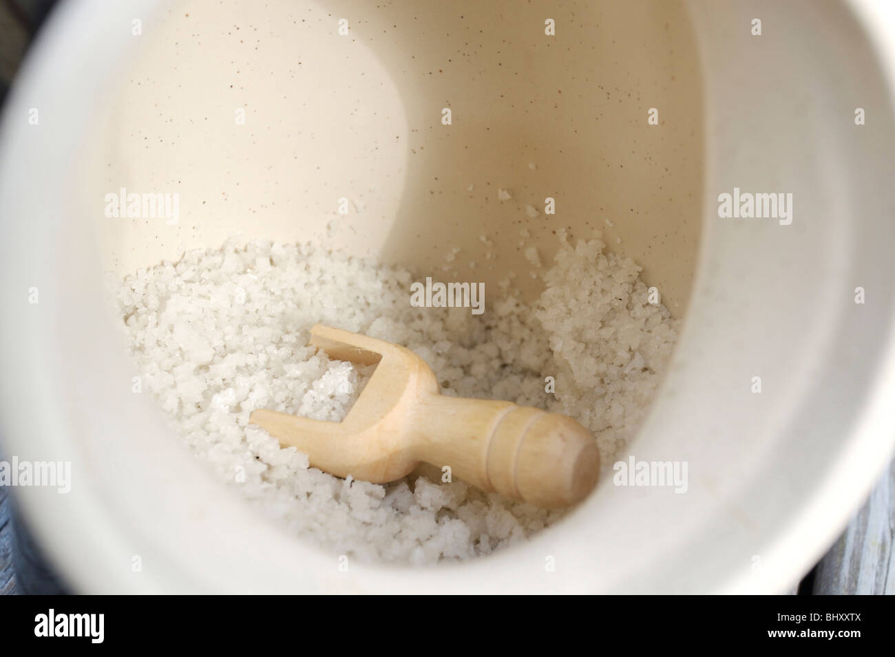 Le sel de mer dans un récipient avec une cuillère en bois Banque D'Images