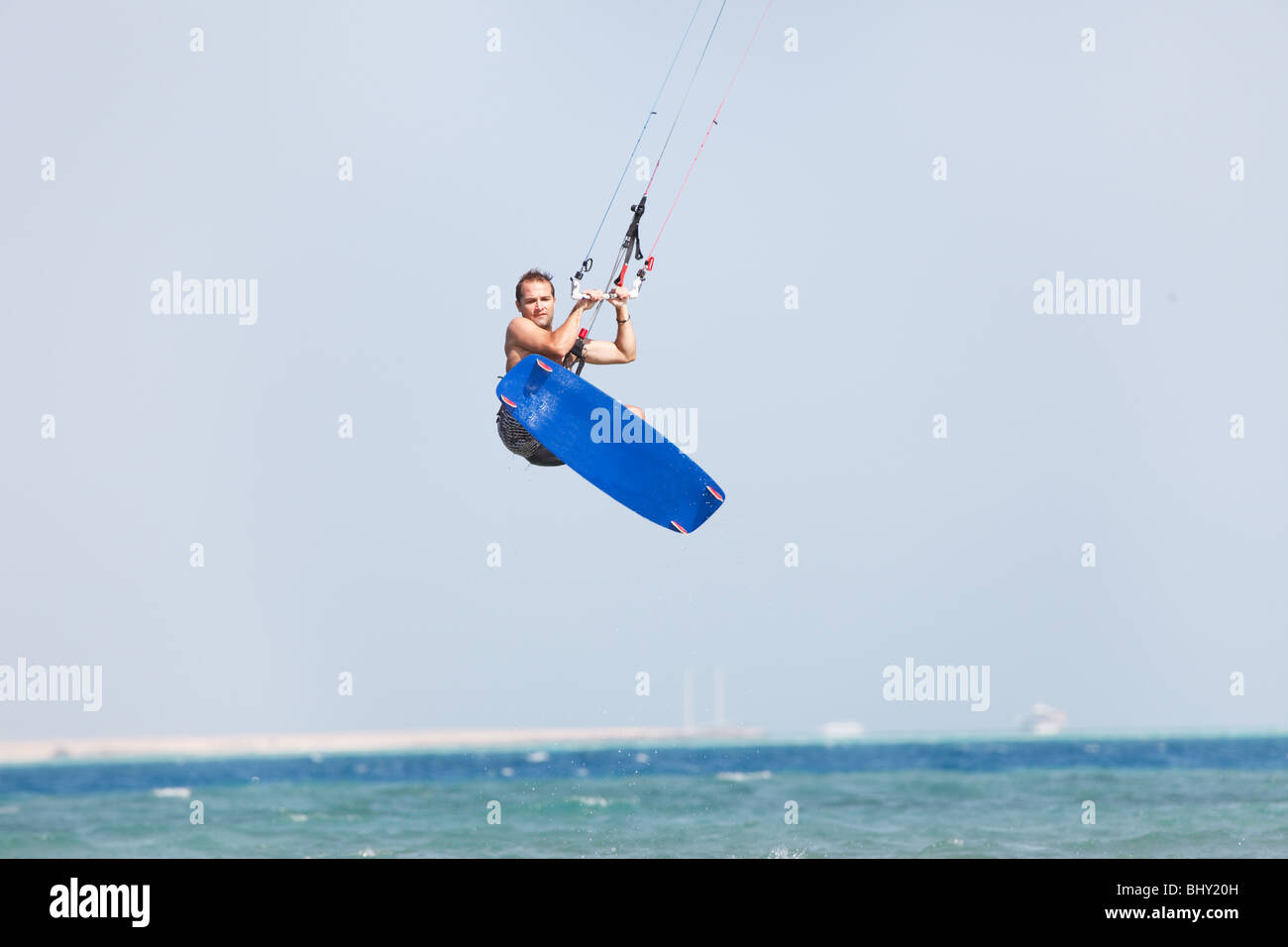 Kiteboarder faire du surf dans l'eau bleu et saute haut dans les airs. Banque D'Images