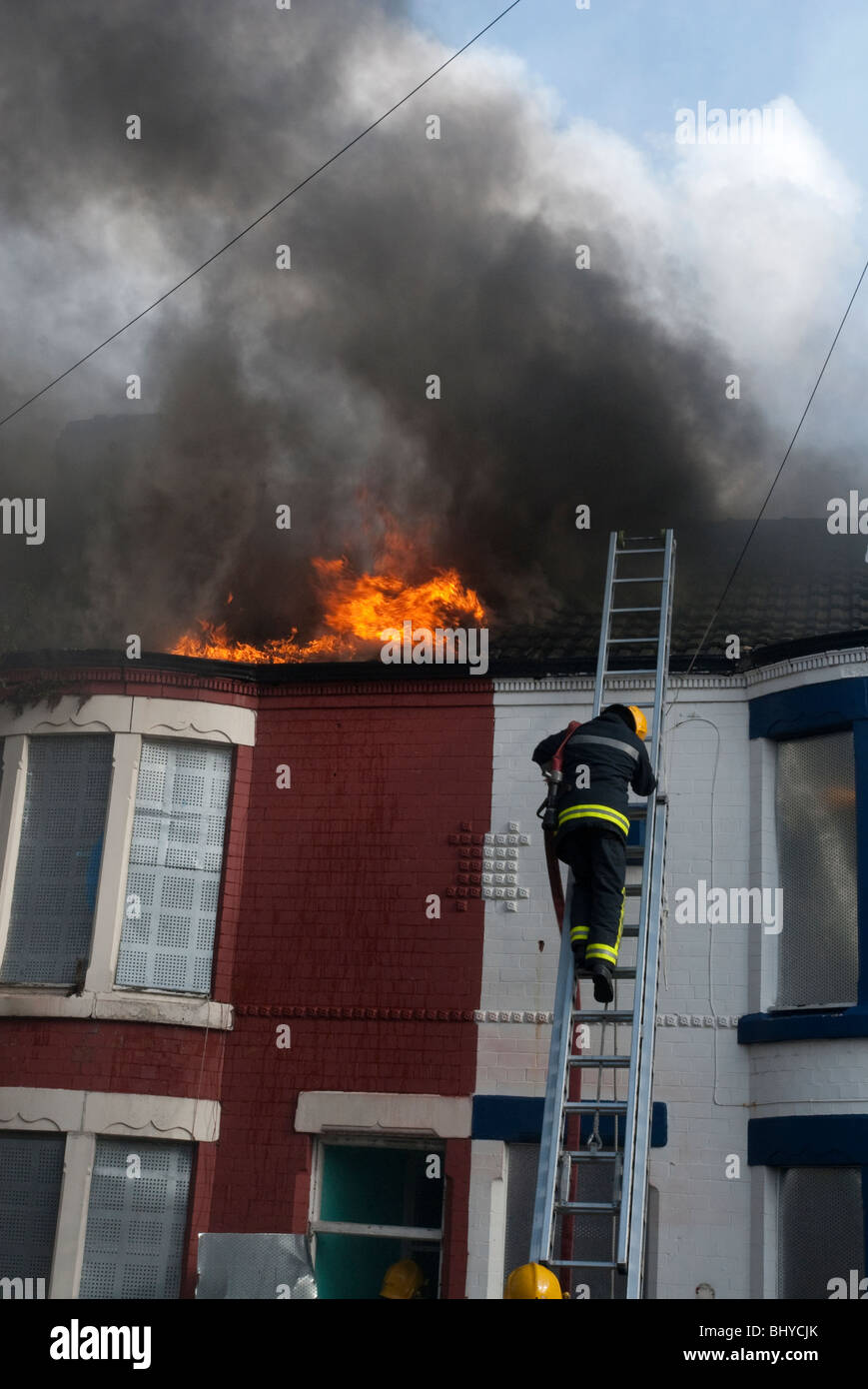 Maison mitoyenne sur le feu avec de la fumée et des flammes qui sortent du toit Banque D'Images