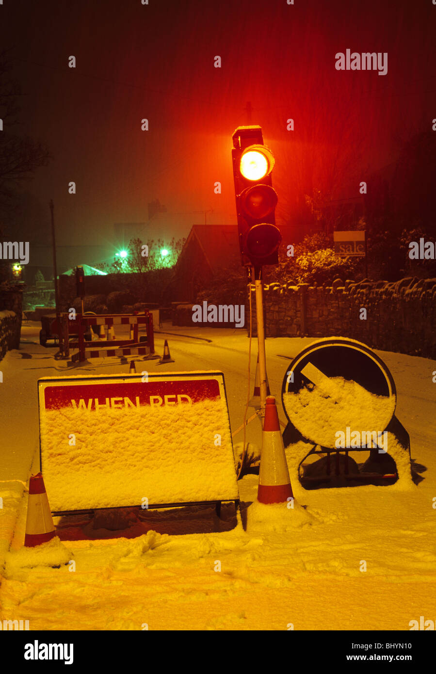 Le feu rouge à travaux routiers dans la région de neige de l'hiver dans la nuit près de Leeds Yorkshire UK Banque D'Images