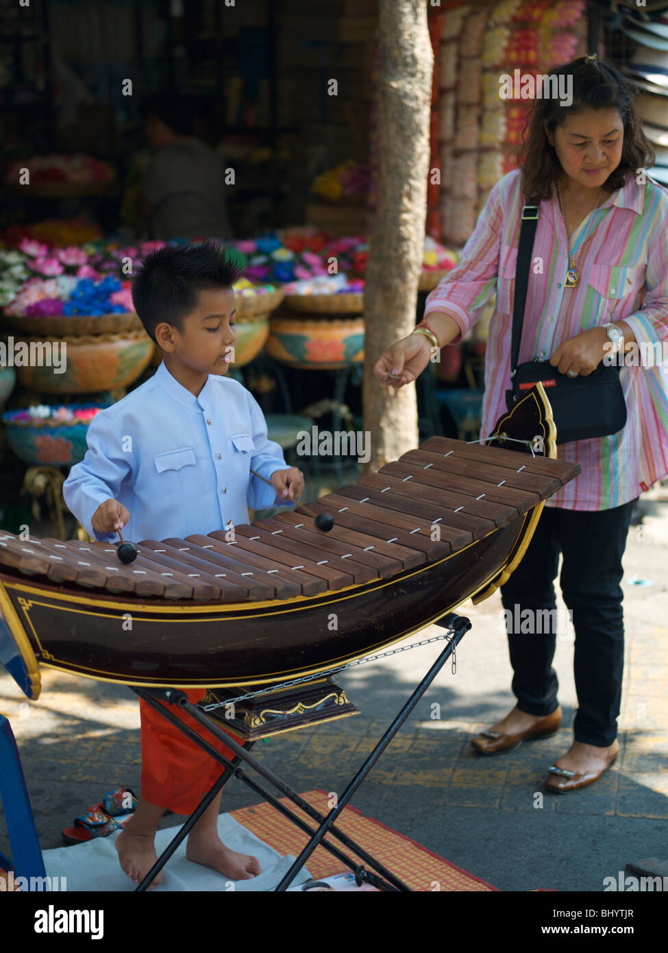 Jeune garçon joue de la musique pour les acheteurs à la marché du weekend de Chatuchak à Bangkok en Thaïlande Banque D'Images