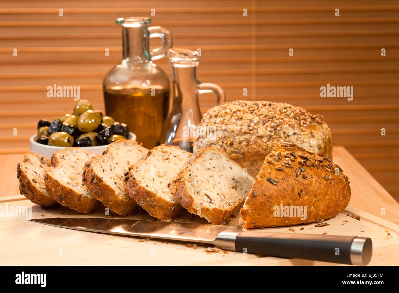 Frais coupé en tranches de pain rustique et ensemencées avec un couteau et un bol de green & black olives, l'huile d'olive & vinaigre balsamique Banque D'Images