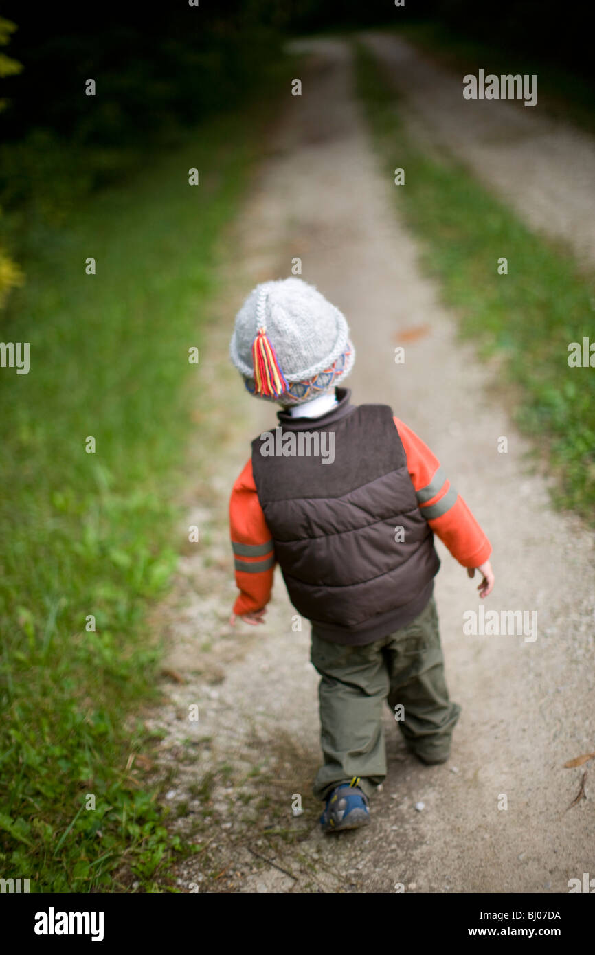 Jeune garçon marchant sur une route de gravier. Banque D'Images