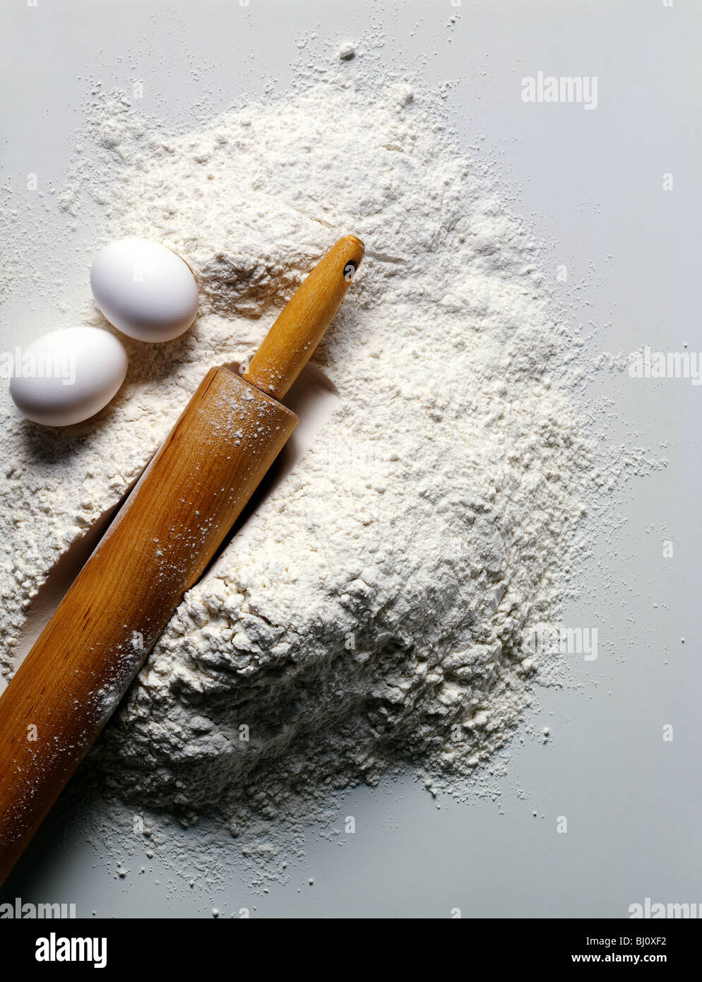 La vie encore d'œufs, de farine et de rouleau à pâtisserie sur un fond blanc. Banque D'Images