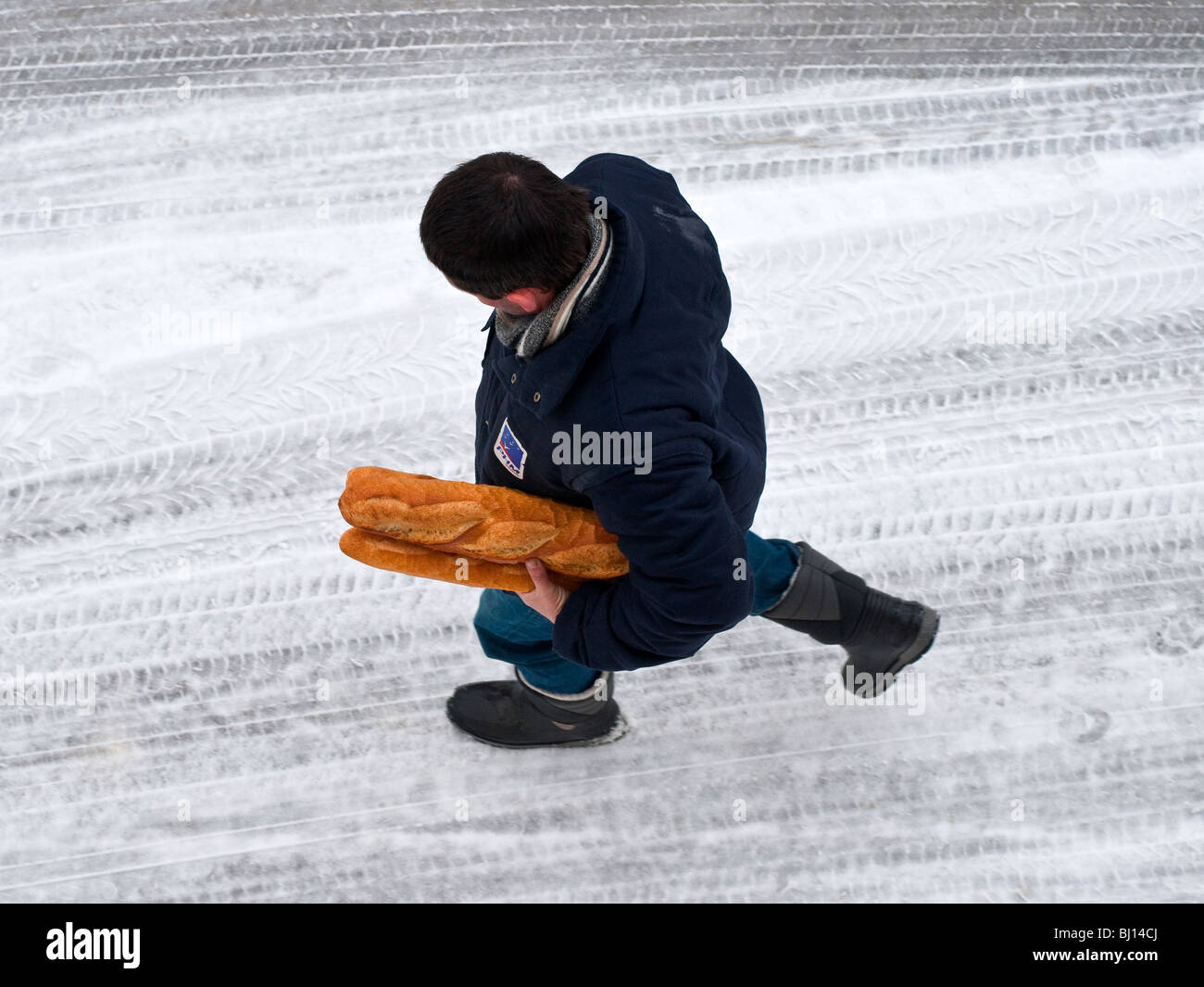 Man holding pain marche sur route couverte de neige - France. Banque D'Images