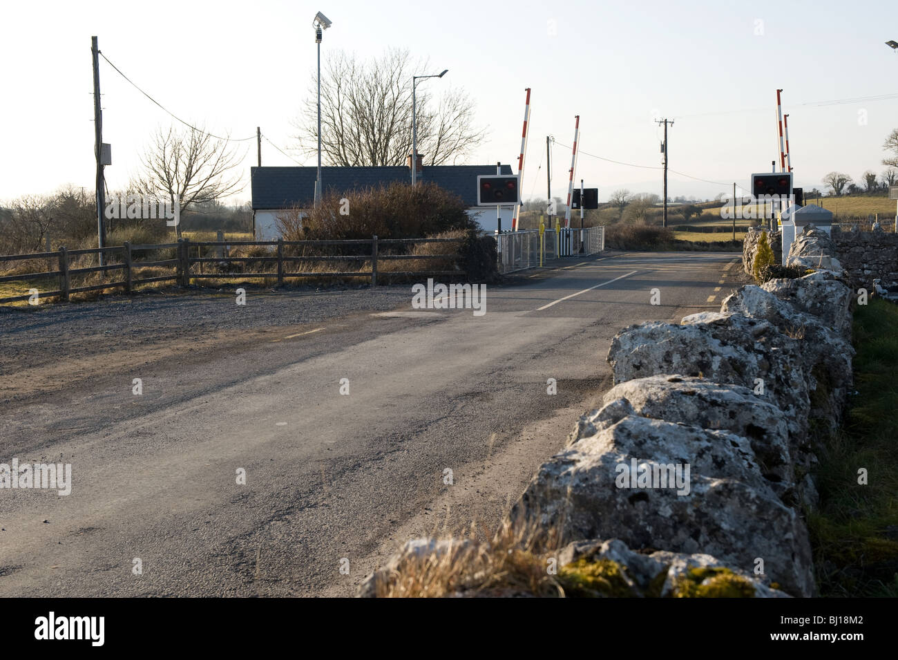 Mur de pierre menant à un passage à niveau moderne sur une étroite route de campagne, le comté de Mayo, Irlande. Banque D'Images