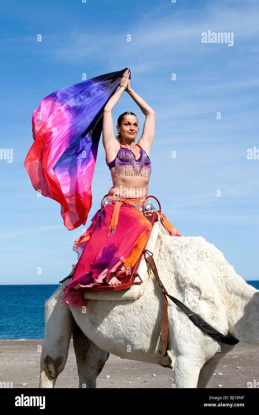 Danseuse du Ventre assis sur un chameau avec voile de couleur dans le vent Banque D'Images