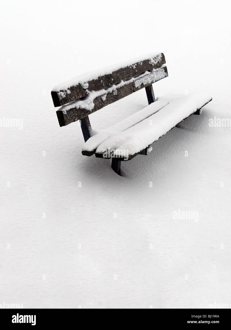 Banc en bois en dévers park couvert de neige Banque D'Images