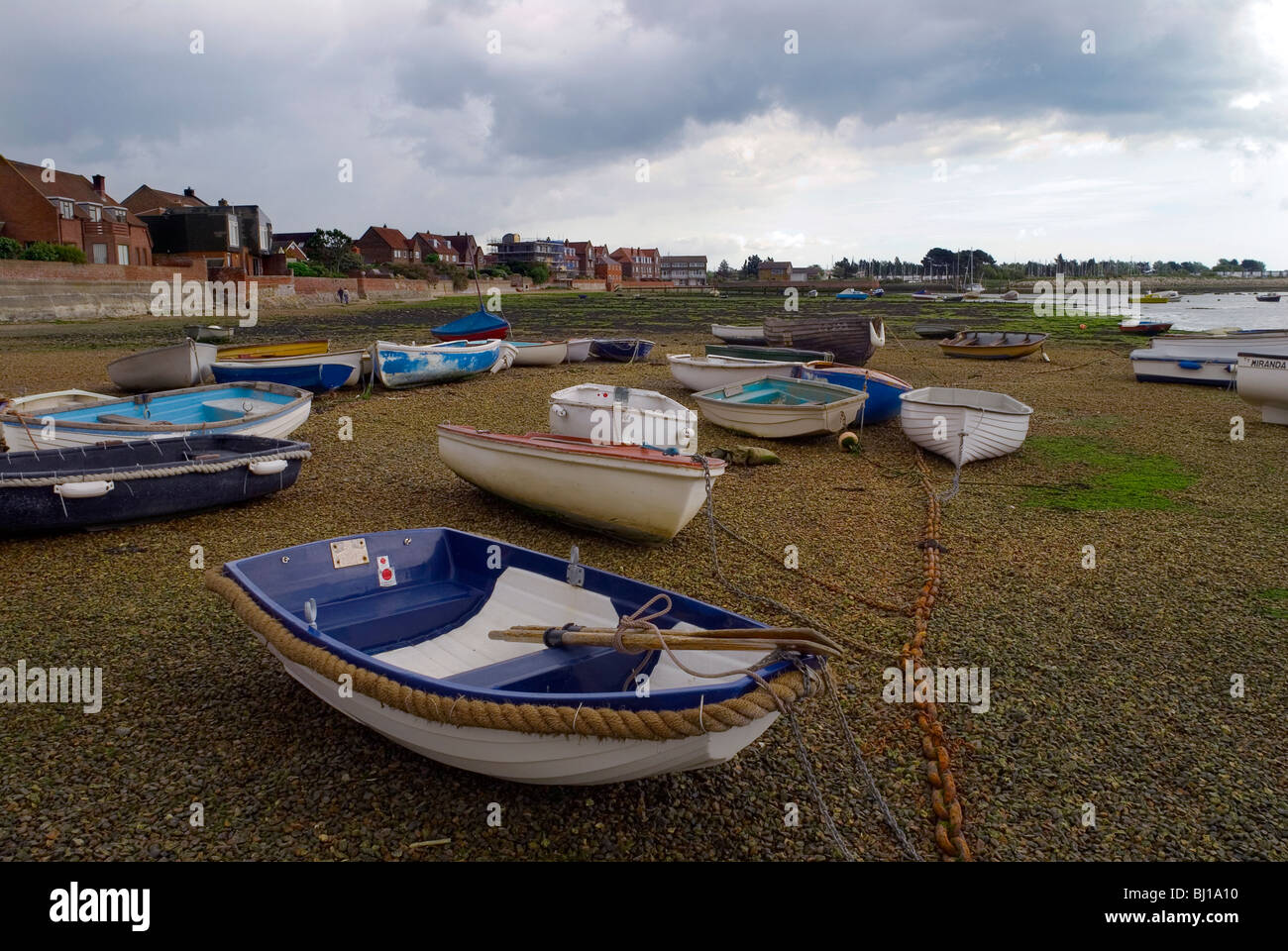 Bateaux allongé sur le lit de la mer à Emsworth Harbour avec la marée basse et de l'habitation le long de la parade dans l'arrière-plan Banque D'Images