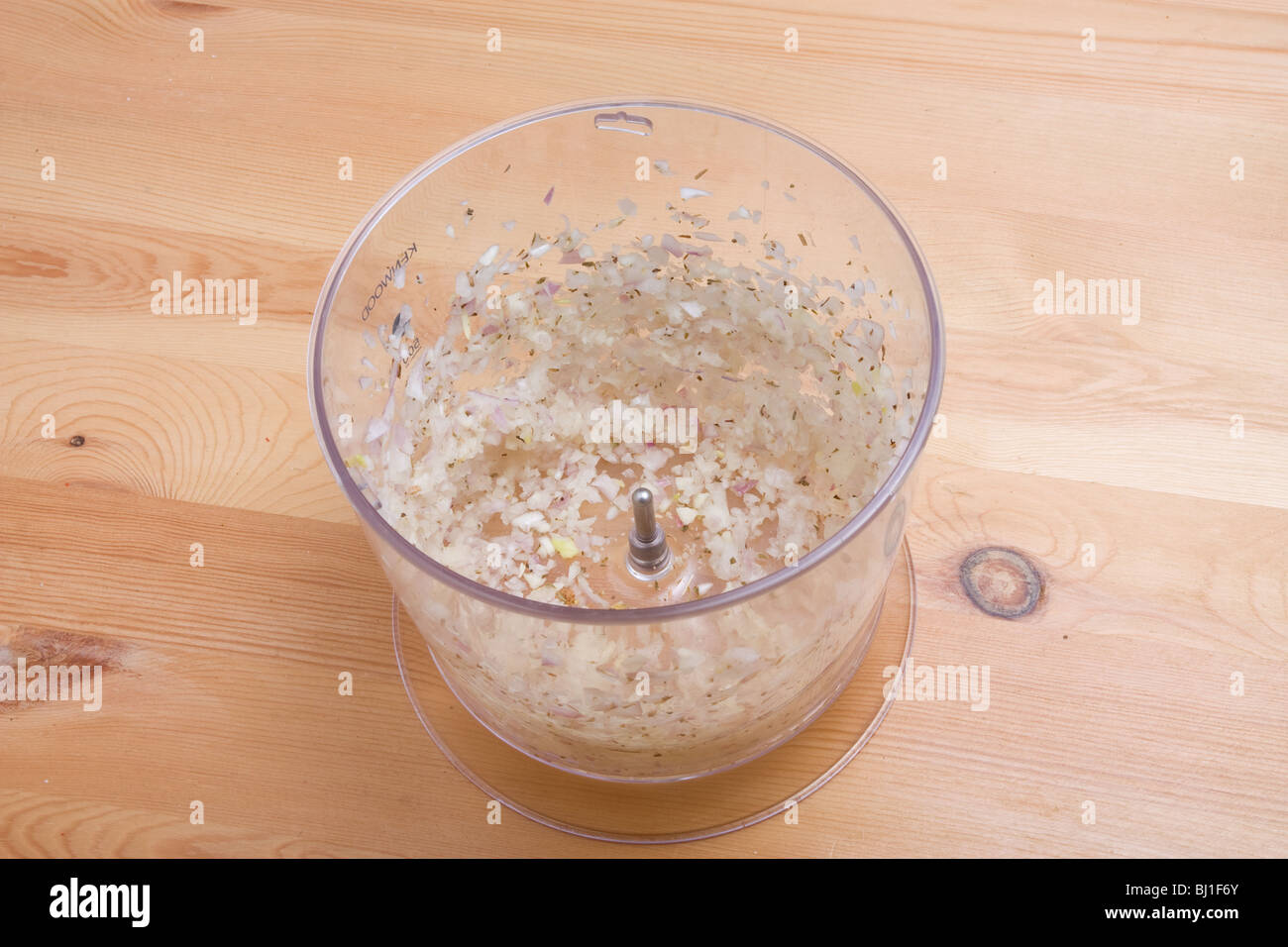 Aliments transformés finement hachés échalote dans un contenant de plastique sur la surface de travail en bois. Banque D'Images