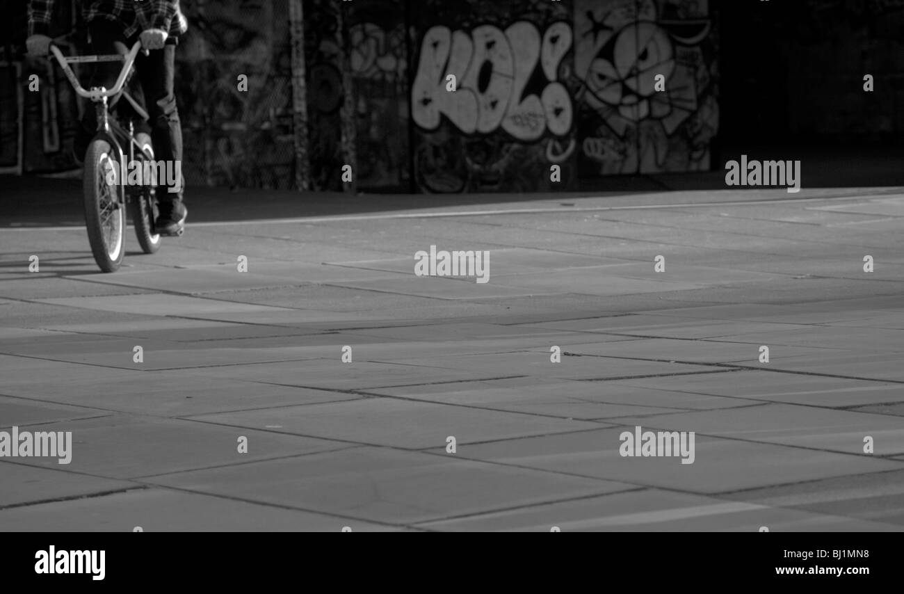 Image conceptuelle d'un adolescent sur un vélo à côté d'un mur recouvert de graffitis, prises le London's South Bank. Banque D'Images