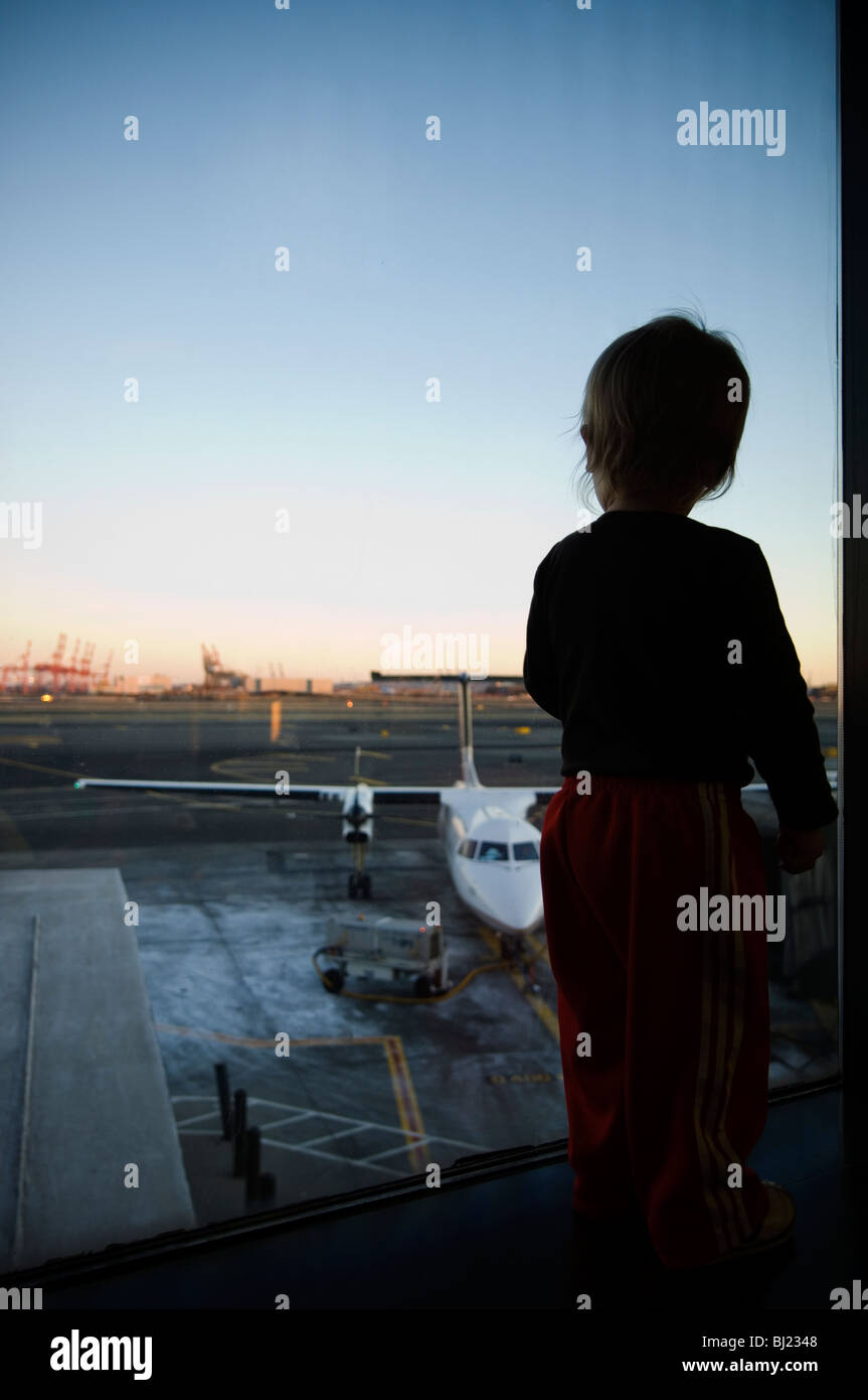 Un garçon regardant une par une fenêtre de l'aérodrome Banque D'Images