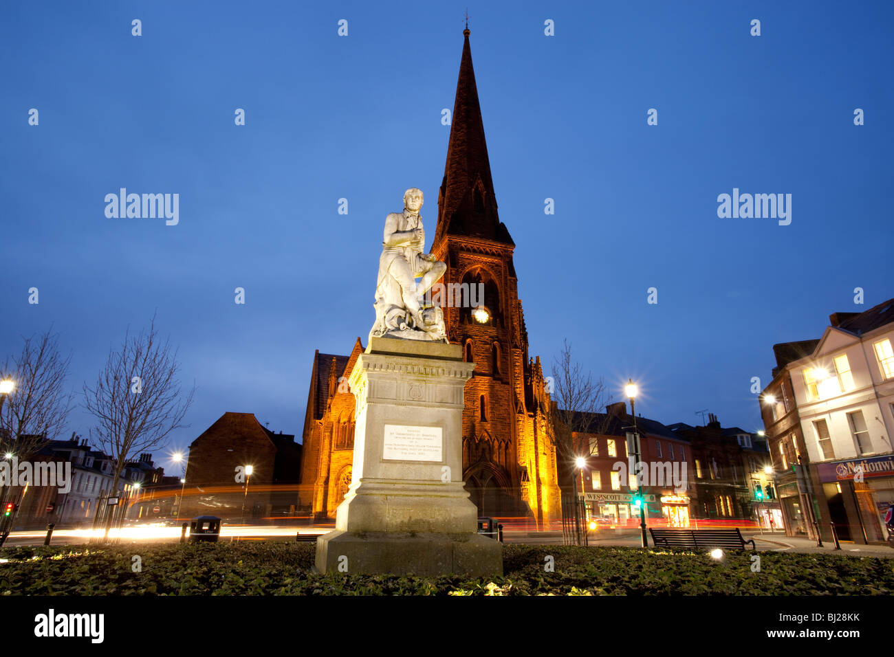 Le poète Robert Burns statue en Dumfries centre-ville avec l'église de Greyfriars derrière la nuit Ecosse UK Banque D'Images