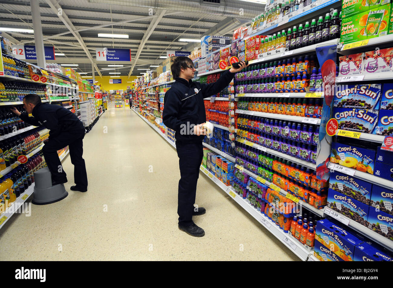 Stock de travailleurs les étagères et vérifier les prix dans un magasin Tesco Banque D'Images