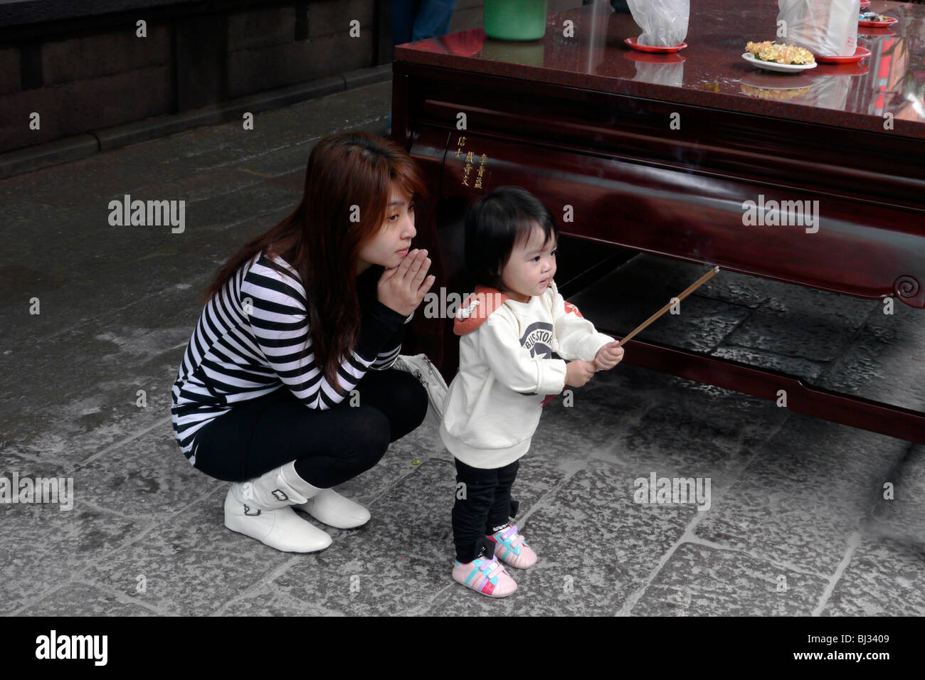 Temple Lungshan TAIWAN, Taipei. Les gens de prier. Une mère de famille. Photographie par SEAN SPRAGUE Banque D'Images