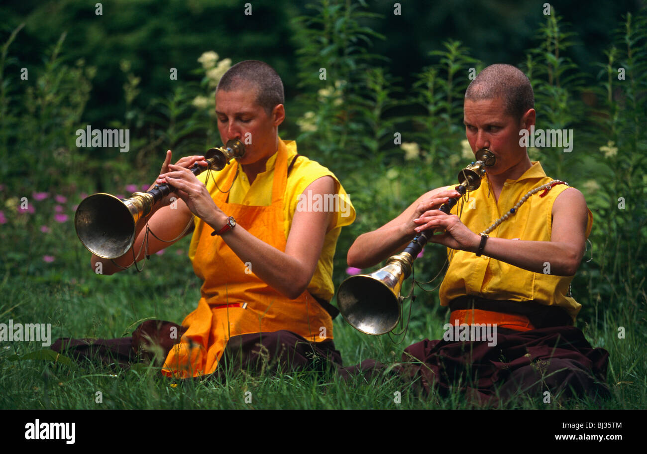 Deux moniales de l'Tibetan-Buddhism Rag-Dung suivants jouent leurs trompettes (laiton) dans un jardin à l'Kagyu Samye Ling Monastery. Banque D'Images