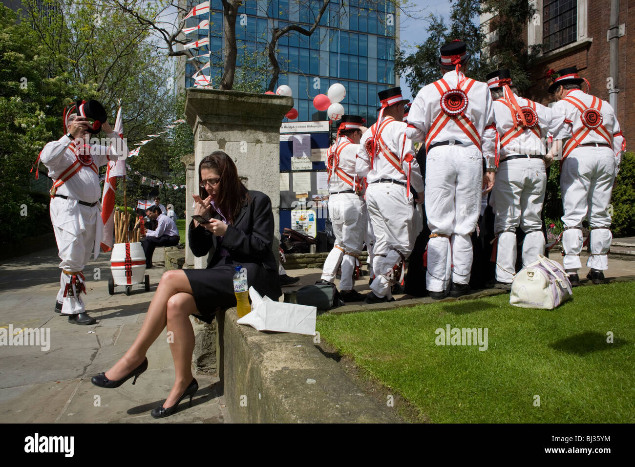 Une dame employée de bureau essaie de profiter de son midi en soleil du printemps, ne pas tenir compte d'un groupe de musique traditionnel de Morris Men. Banque D'Images