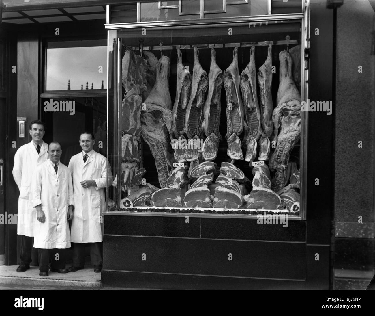 Les bouchers debout à côté de leur shop Window display, South Yorkshire, 1955. Artiste : Michael Walters Banque D'Images