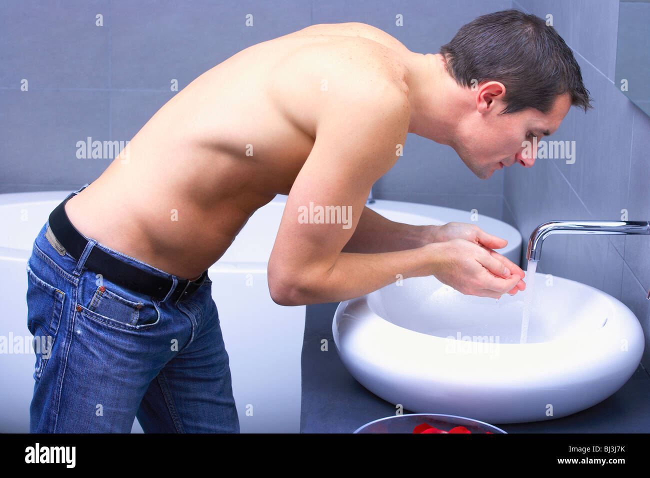 L'homme en face de flexion d'un robinet Banque D'Images
