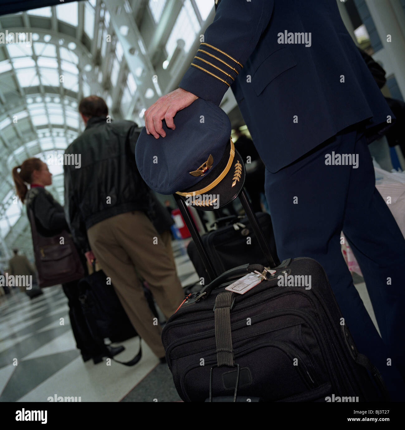 Attente en ligne pour un vol au départ, le capitaine d'une compagnie aérienne avec ses files d'patiemment les bagages du vol avec passagers. Banque D'Images