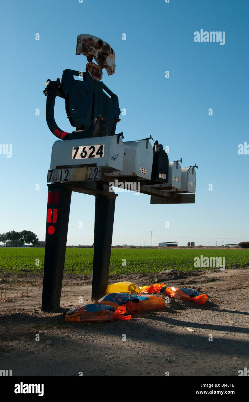Un robot d'acier figure détient cinq boîtes mail sur une route rurale en Californie. Banque D'Images