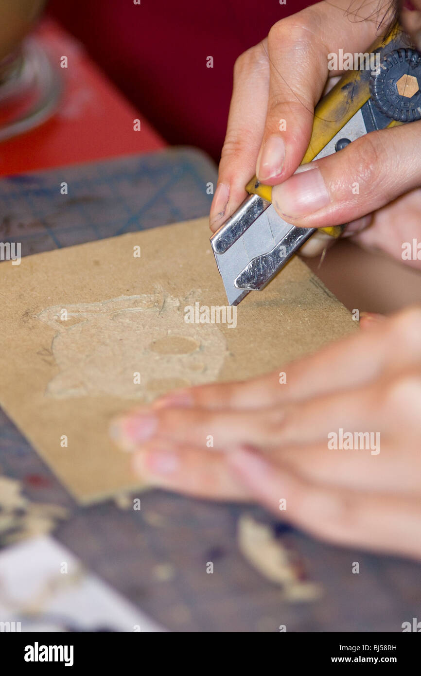 Artiste à l'aide d'une lame de rasoir couteau pour couper une gravure dans le livre. Banque D'Images